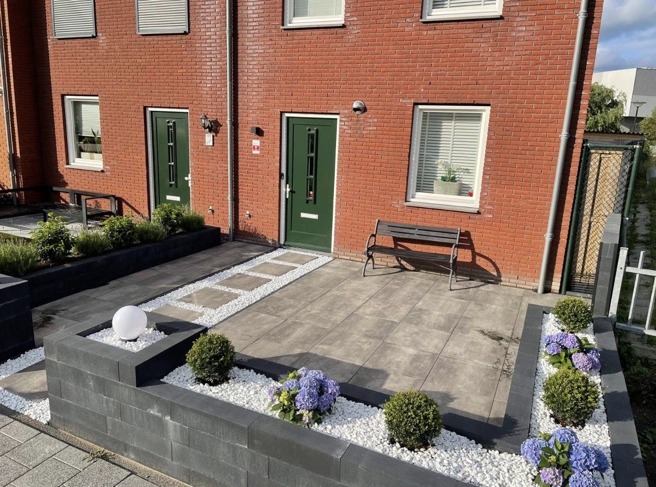 Voortuin met tegels, stapelblokken, witte split en hortensia's